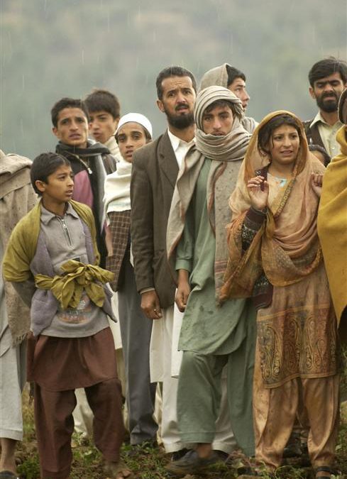 Village residents wait as Pakistani soldiers unload disaster relief supplie